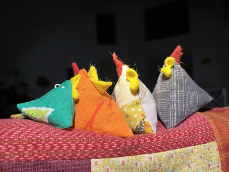 photo of a row of fabric chickens on top of a sewing machine that was has a a patchwork cover on top.